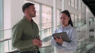 İki yönetici iş projesini tartışıyor ofiste duruyor ve notlar alıyor.