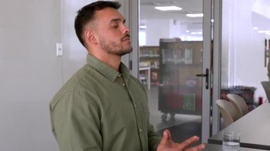 Genç erkek çalışan ofiste meditasyon yapıyor. Masada oturuyor. 