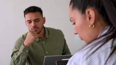 Genç endişeli adam ve bayan meslektaşı ofiste birlikte çalışıyorlar.