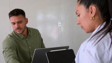 Genç endişeli adam ve bayan meslektaşı ofiste birlikte çalışıyorlar.