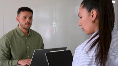 Genç endişeli adam ve bayan meslektaşı ofiste birlikte çalışıyorlar.