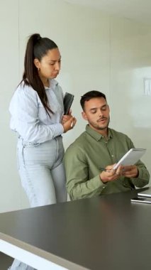 İki iş arkadaşı bir projeyi tartışıyor, fikirleri paylaşıyor, adam defterlere bakıyor.