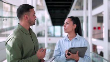 İki yönetici iş projesini tartışıyor ofiste birlikte yürüyor ve notlar alıyorlar.