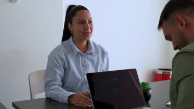 İki iş arkadaşı bir projeyi tartışıyor. Kadın ve erkek, masada oturmuş birbirlerinin önünde aletlerle iletişim kuruyorlar.