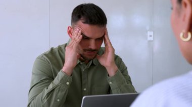 Genç endişeli adam ve bayan meslektaşı ofiste birlikte çalışıyorlar.