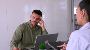 Genç endişeli adam ve bayan meslektaşı ofiste birlikte çalışıyorlar.