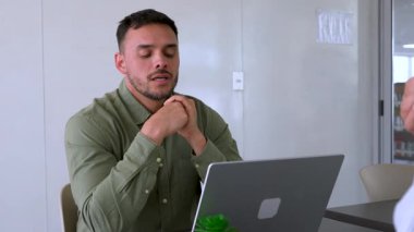 Genç endişeli adam ve bayan meslektaşı ofiste birlikte çalışıyorlar.