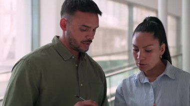 İki yönetici iş projesini tartışıyor ofiste duruyor ve notlar alıyor.