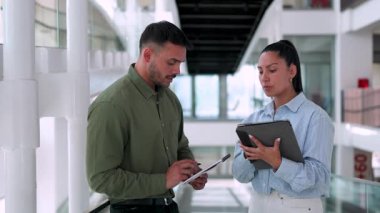 İki yönetici iş projesini tartışıyor ofiste birlikte yürüyor ve notlar alıyorlar.