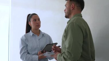 Genç iş çifti ofiste konuşuyor ve notlar alıyor.