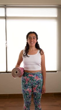Genç Latin kadın, yoga minderini egzersiz için hazır tutuyor. 