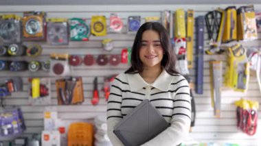 Küçük oto yedek parça mağazasında elinde dijital tablet tutan Latin Amerikalı satıcı.