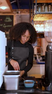 Genç Afrikalı Amerikalı barista kahve makinesiyle kahve hazırlıyor.