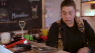 Kadın kasiyer bir kahve dükkanının kasasında para ve makbuz yönetiyor.