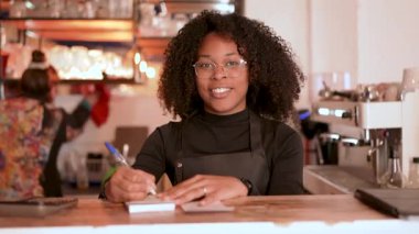 Afro-Amerikalı garson rahat kahve dükkanında müşteri siparişi yazıyor.