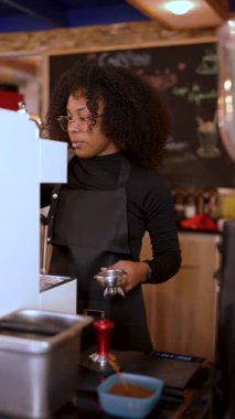 Genç Afrikalı Amerikalı barista kahve makinesiyle kahve hazırlıyor.