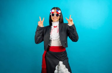 Neşeli güneş gözlüğü takan gülümseyen kadın barış işareti yapıyor.