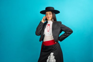 Geleneksel kostüm giymiş gülümseyen bir kadın telefonda konuşuyor.