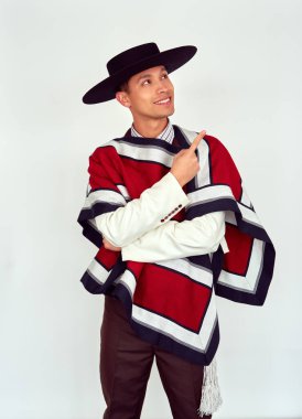 Geleneksel giyinmiş Şili Huaso yukarı bakıyor ve işaret parmağıyla işaret ediyor: