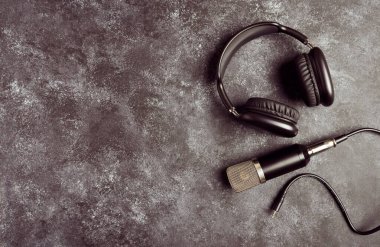 Podcast prodüksiyonu için arka planda kulaklığı olan profesyonel bir mikrofon.