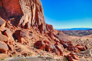 Şiddetli aşınmış kırmızı kumtaşı kayaları ve Nevada, ABD 'deki Fire State Park Vadisi' ndeki seyrek çöl bitkileriyle manzara..