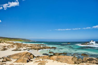 Batı Avustralya 'nın Margaret Nehri bölgesindeki Leeuwin-Naturaliste Ulusal Parkı kıyısında birkaç turistin bulunduğu Redgate' teki kayalık plaj.