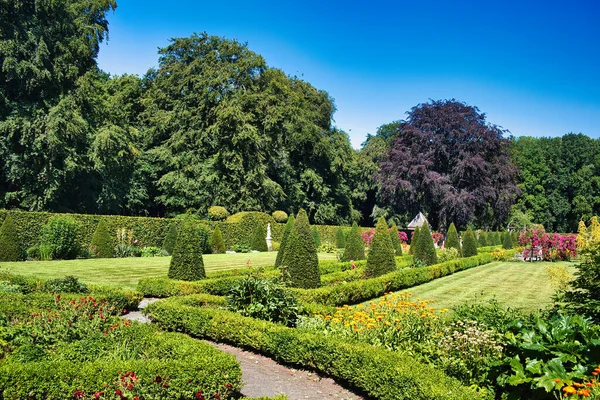 Formal French garden with topiary, flower beds, hedges, lawns and tall trees around castle Menkemaborg, Uithuizen, province of Groningen, the Netherlands