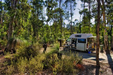Batı Avustralya, Perth yakınlarındaki Avon Valley Ulusal Parkı 'nda küçük bir karavanla çim ağaçları ve okaliptüslü bir yerde kamp yapmak..