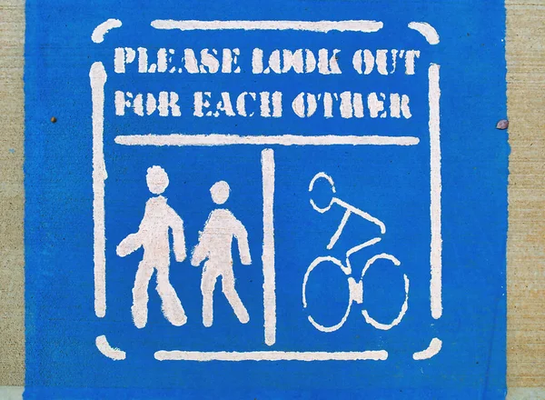 Painted sign on a shared bicycle path and footpath urging users to look out for each other, Australia