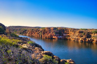 Batı Avustralya 'daki Cape Range Ulusal Parkı' ndaki Yardie Deresi geçidi, kırmızı kireçtaşı kayaları ve bodur taşra bitki örtüsüyle.