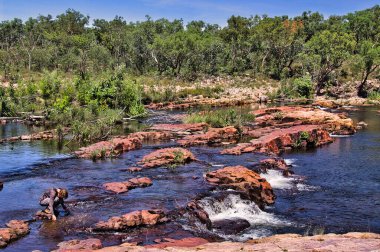 Yürüyüşçü, Crystal Falls bölgesindeki Jatbula Patikası boyunca uzanan tropikal Nitmiluk Ulusal Parkı, Katherine, Kuzey Bölgesi, Avustralya 'da serin su püskürtür.