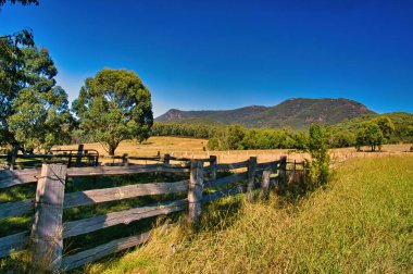 Ormanlı tepelerin eteğindeki çayırda yıpranmış ahşap bir tahta çit. Victoria, Avustralya 'nın Alp bölgesinde Kiewa Vadisi.
