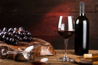 Kırmızı şarap kadehi ve masada taze üzümlü bir şarap şişesi..