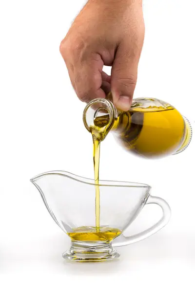 将初榨橄榄油倒入碗中的水壶 — 图库照片