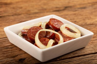 Sliced sausage with onion on wooden background. clipart