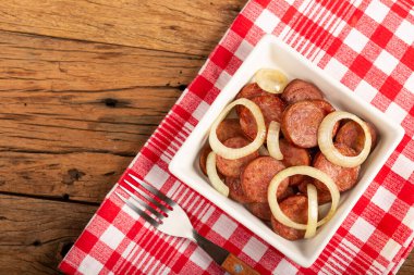 Sliced sausage with onion on wooden background. clipart