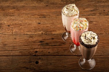 Üç bardak çeşitli aromalı milkshake. Çikolata, vanilya ve çilekli milkshake..