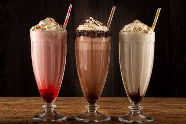 Üç bardak çeşitli aromalı milkshake. Çikolata, vanilya ve çilekli milkshake..