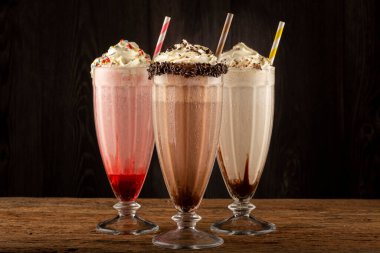 Üç bardak çeşitli aromalı milkshake. Çikolata, vanilya ve çilekli milkshake..