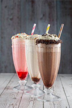 Üç bardak çeşitli aromalı milkshake. Çikolata, vanilya ve çilekli milkshake..