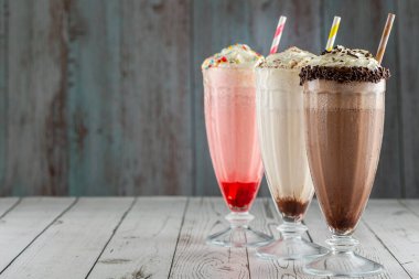 Üç bardak çeşitli aromalı milkshake. Çikolata, vanilya ve çilekli milkshake..