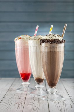 Üç bardak çeşitli aromalı milkshake. Çikolata, vanilya ve çilekli milkshake..