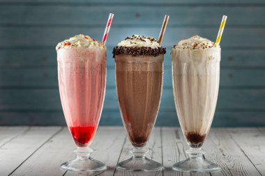 Üç bardak çeşitli aromalı milkshake. Çikolata, vanilya ve çilekli milkshake..
