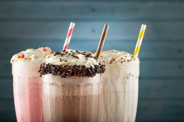 Üç bardak çeşitli aromalı milkshake. Çikolata, vanilya ve çilekli milkshake..