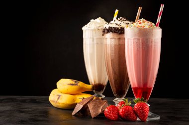 Üç bardak çeşitli aromalı milkshake. Çikolata, vanilya ve çilekli milkshake..