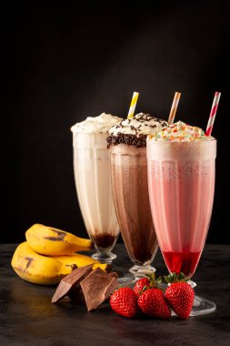 Üç bardak çeşitli aromalı milkshake. Çikolata, vanilya ve çilekli milkshake..