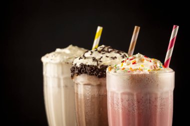 Üç bardak çeşitli aromalı milkshake. Çikolata, vanilya ve çilekli milkshake..
