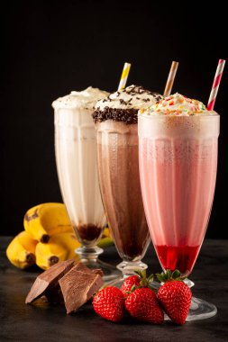 Üç bardak çeşitli aromalı milkshake. Çikolata, vanilya ve çilekli milkshake..