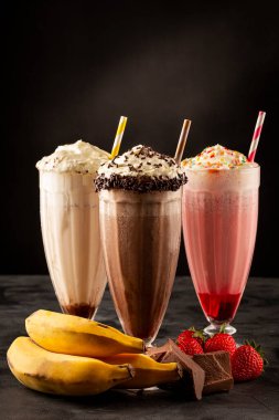 Üç bardak çeşitli aromalı milkshake. Çikolata, vanilya ve çilekli milkshake..