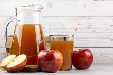 Elma suyu ve kırmızı elmalar masada..